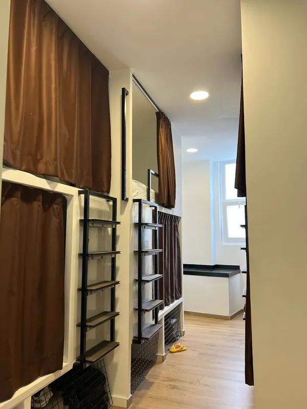 Literas tipo cápsula con cortinas marrones en una habitación para grupos