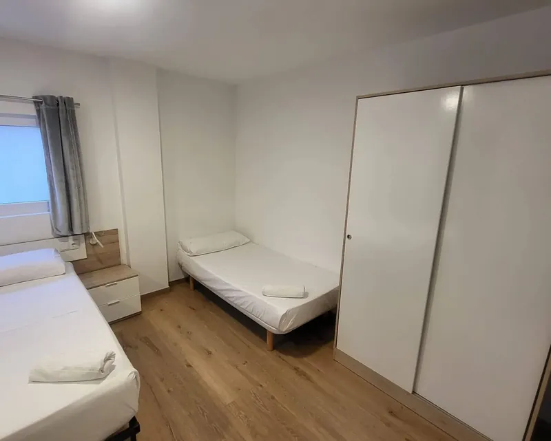 Habitación con camas, armario y ventana en el alojamiento para grupos