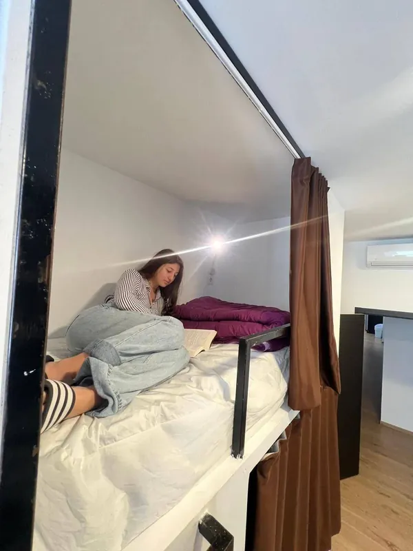 Cápsula individual con cortina y cama hecha en el alojamiento para despedidas