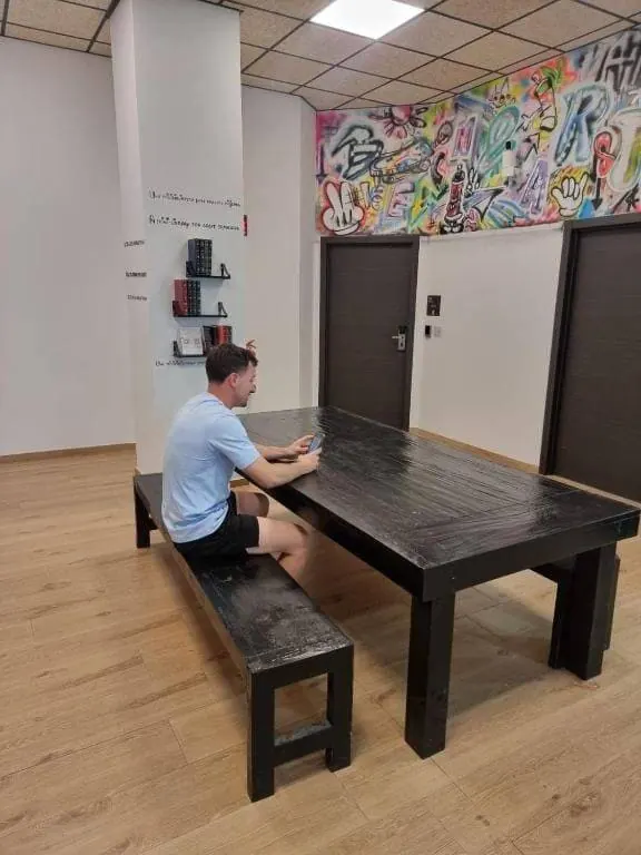 Sala común con mesa y banco junto a las habitaciones del alojamiento